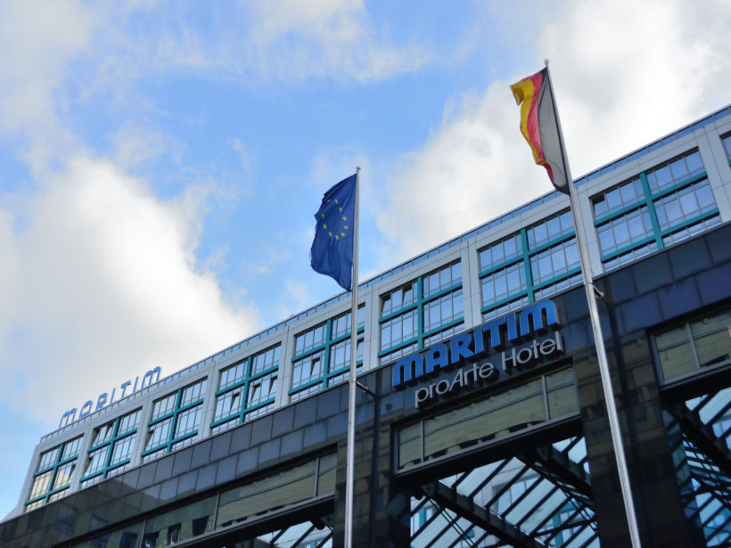 Gebäude mit großer Glasfassade, Flaggen davor.